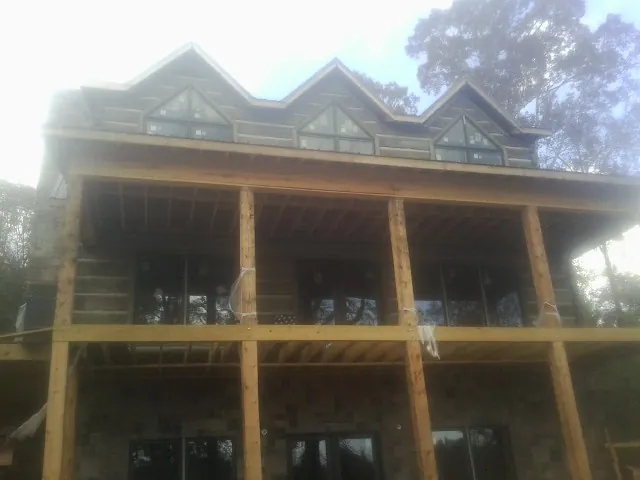 Dormers and porch framing on a large log home under construction — Roof Coating work by our crew in Choctaw