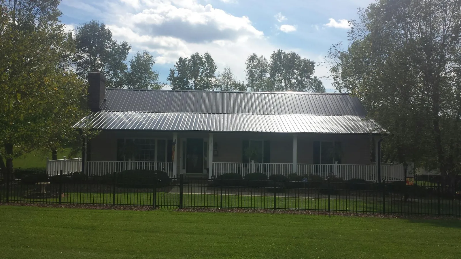 Gray metal roof on a brick ranch with a full width front porch — Gutter Guard Installation work by our crew in Choctaw