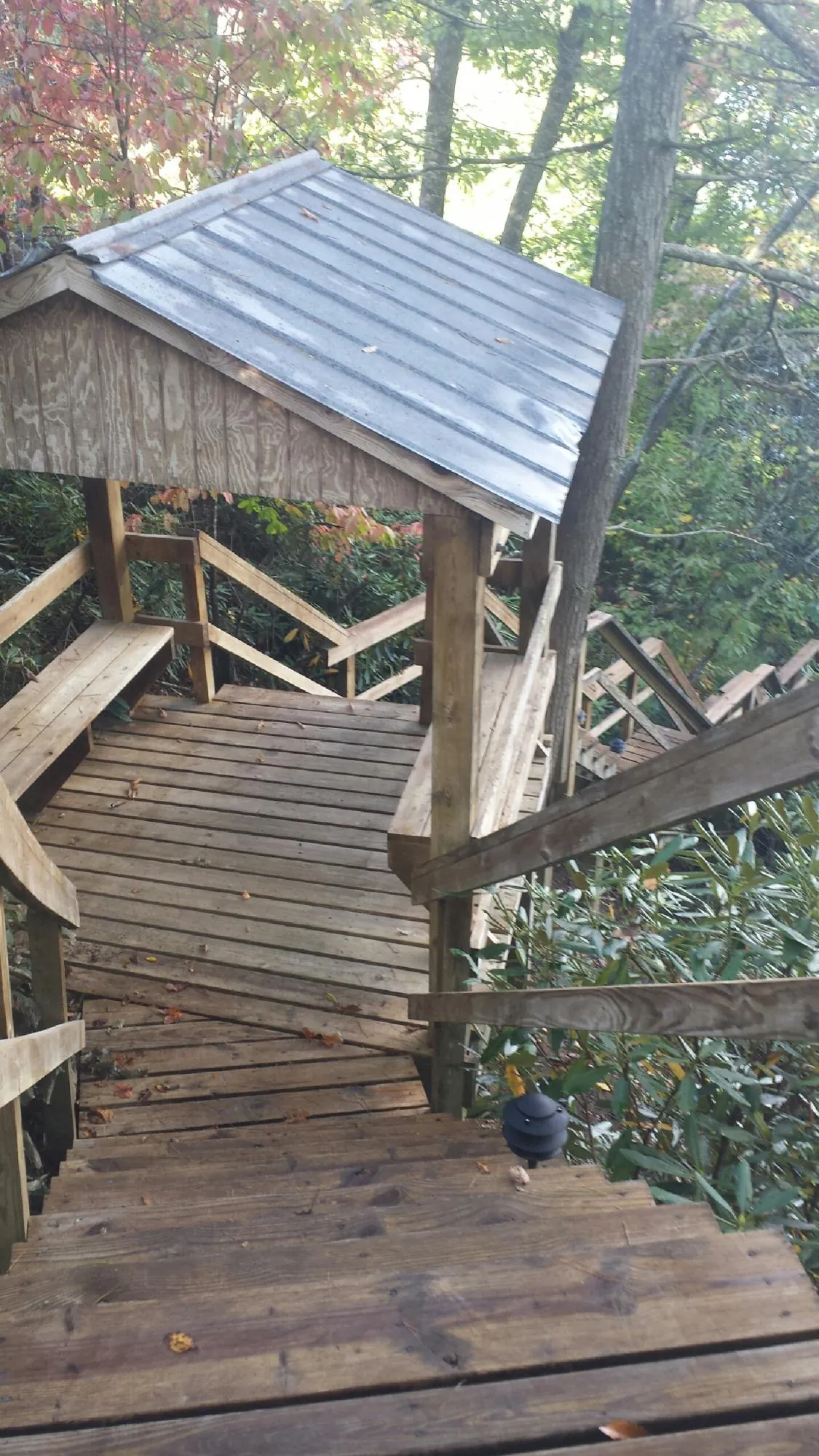Metal roofed shelter over wooden steps on a wooded walkway — Skylight Repair & Installation work by our crew in Choctaw
